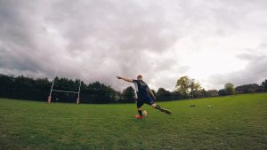 Student kicking rugby ball